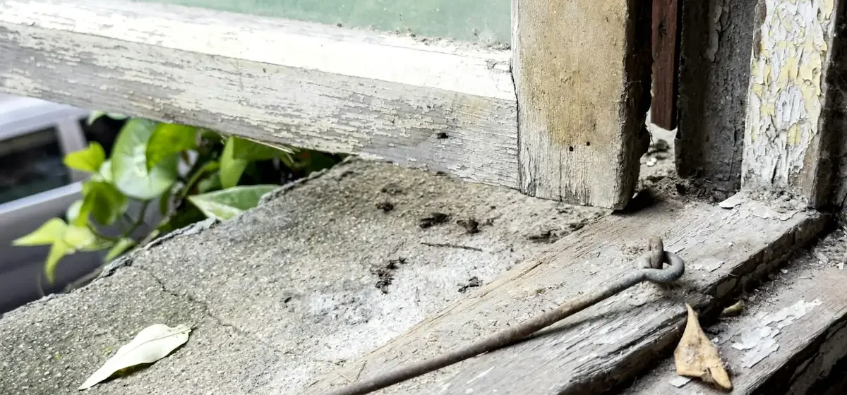 Weathered metal latch on an old window frame