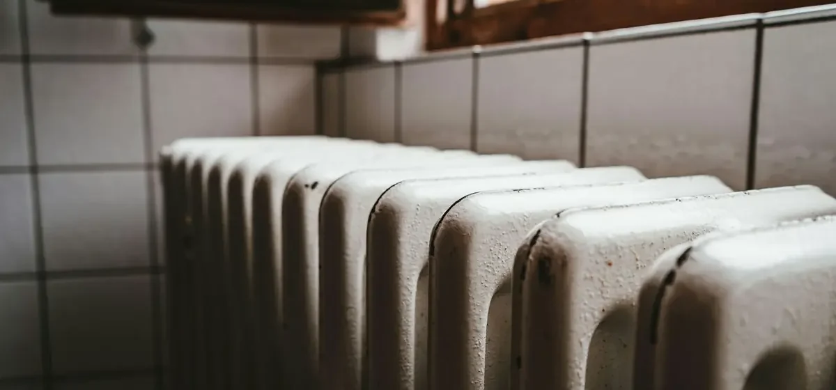 White radiator beside a wooden window frame