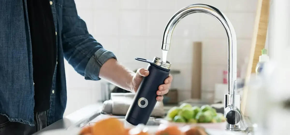 A hand turning a stainless steel tap over a basin
