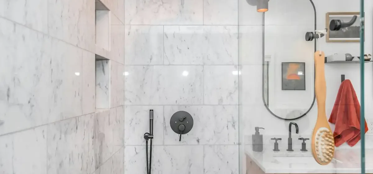 A black shower head mounted on white tiled bathroom walls