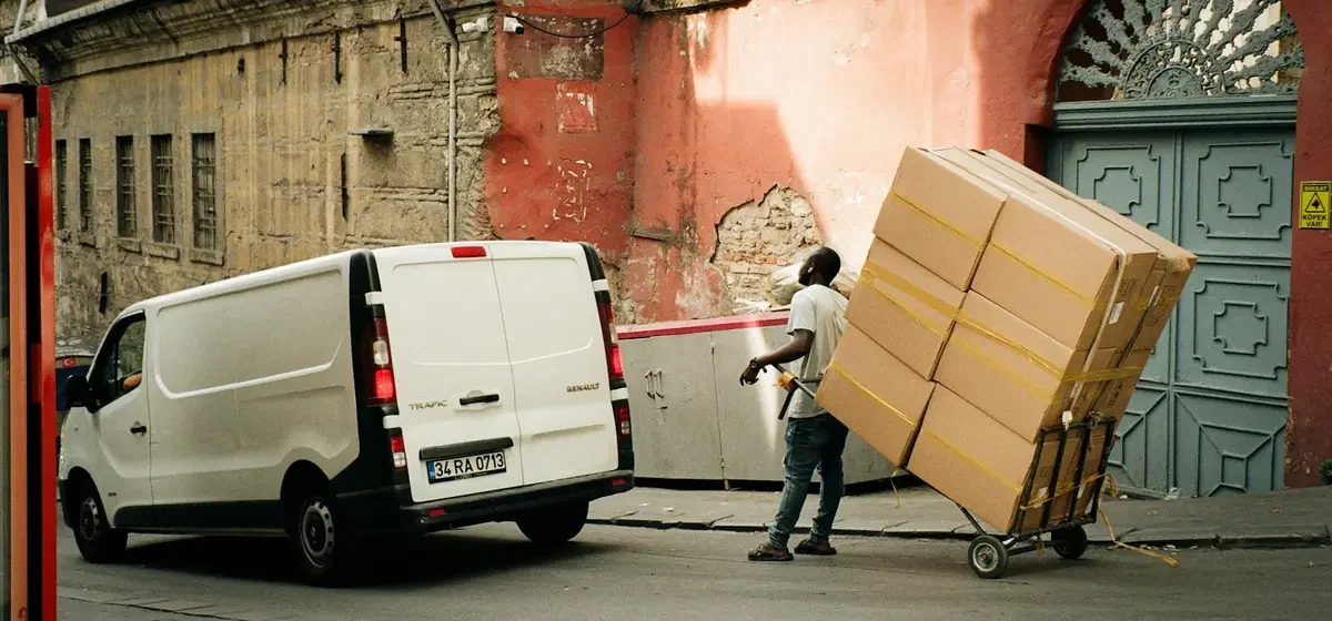 Man unloading cardboard boxes from the rear of a van