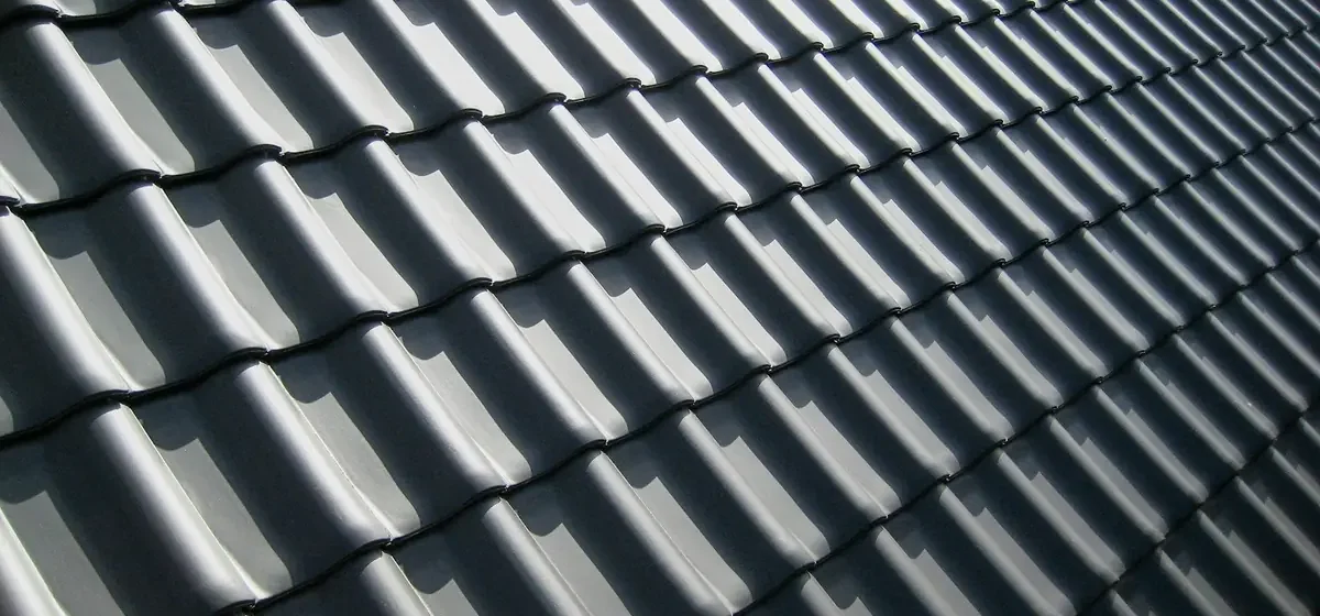 Rows of dark grey roof tiles in bright sunlight