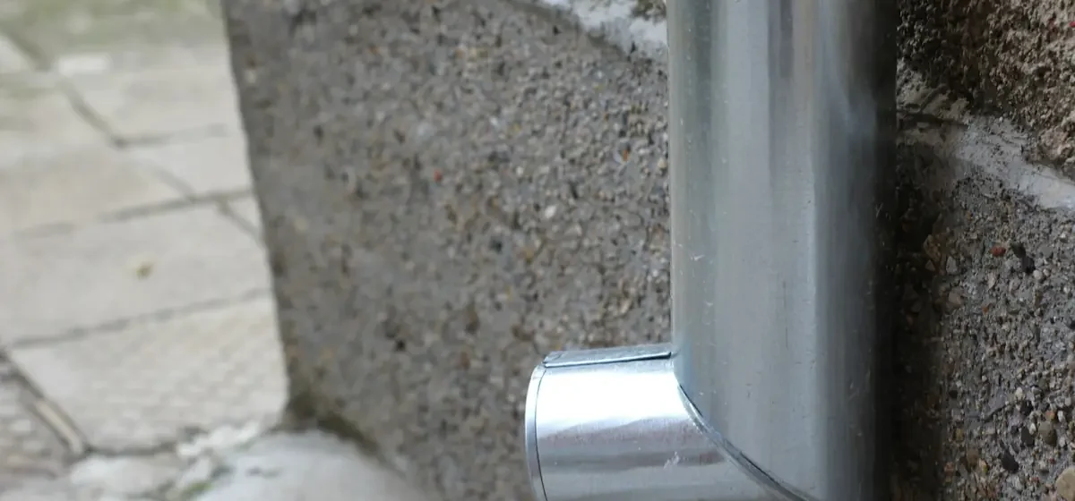 Metal rainwater downpipe fixed to an exterior wall